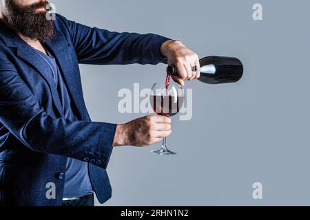 Verser le vin rouge de la bouteille dans le verre à vin. Garçon versant du vin rouge dans un homme sommelier en verre, devéguateur, cave, vigneron masculin. Bouteille, vin rouge Banque D'Images