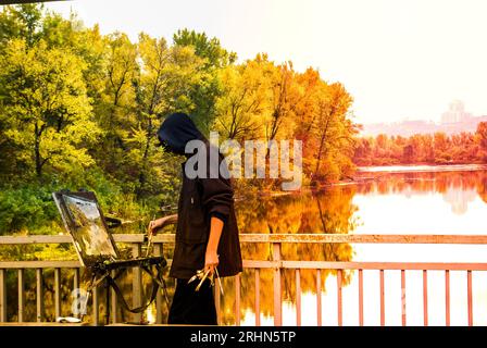 Homme avec chevalet et peinture sur toile dans la nature d'automne Banque D'Images