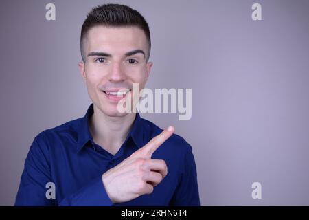 Élégant sourire beau caucasien Young Man points doigt sur le côté sur fond isolé Banque D'Images