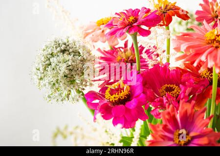 Bouquet d'été de Zinnia colorée, inflorescences d'oignon et brins de menthe, bouquet de fleurs sur la table près du mur, décoration de la maison avec des fleurs Banque D'Images