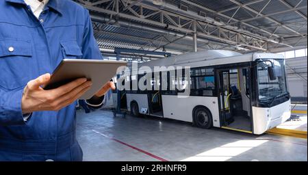 Serviceman avec tablette numérique sur le fond du bus dans le garage. Banque D'Images