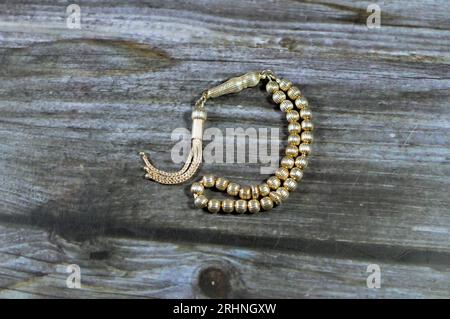 Petit chapelet islamique en couleur argent avec 33 perles de chapelet isolées sur fond de bois, les musulmans l'utilisent pour faire l'éloge d'Allah en utilisant des phrases aux hommes Banque D'Images