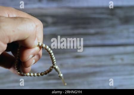 Petit chapelet islamique en couleur argent avec 33 perles de chapelet isolées sur fond de bois, les musulmans l'utilisent pour faire l'éloge d'Allah en utilisant des phrases aux hommes Banque D'Images