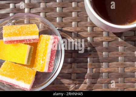 marmelade composée de trois couches saupoudrées de sucre granulé en cubes dans une assiette de verre et de thé dans une tasse de verre. Gros plan. Banque D'Images