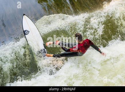 18 août 2023, Bavière, Munich : un surfeur tombe dans l'eau de la vague de surf Floßlände près de la rivière Isar dans le sud de la capitale bavaroise après un tour sur sa planche. Photo : Peter Kneffel/dpa Banque D'Images