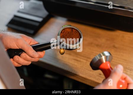 vue rognée du barista dans le support de tablier avec café et presse dans le café Banque D'Images