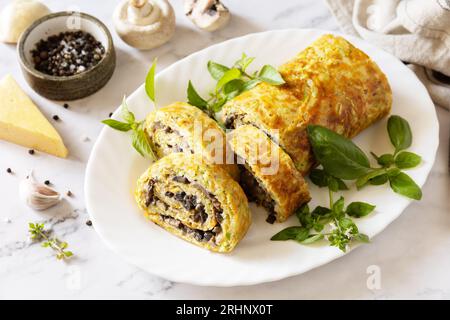 Nourriture végétarienne délicieuse. Rouleau de courgettes (roulade) avec fromage et champignons sur un plateau en marbre. Banque D'Images