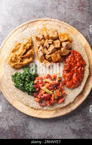 Injera firfir plat pain typique éthiopien petit-déjeuner gros plan sur la planche de bois. Vue verticale de dessus Banque D'Images