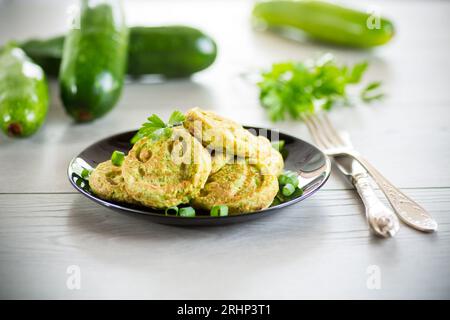 Crêpes vertes de courge frites dans une assiette, sur une table en bois. Banque D'Images