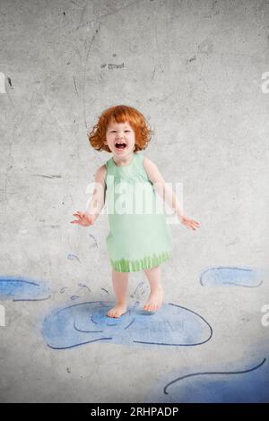 Enfant sautant dans des flaques peintes Banque D'Images