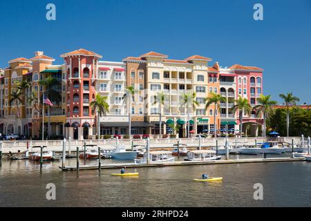 Naples, Floride, États-Unis. Vue de l'autre côté de la rivière Gordon à l'architecture colorée de Bayfront place, kayakistes traversant la marina. Banque D'Images