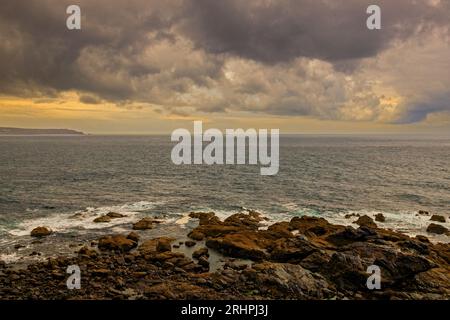 Vue vers le sud depuis le cap Cornwall vers LANd's End et le phare de Longships sous des nuages sombres et spectaculaires, Cornwall, Angleterre, Royaume-Uni Banque D'Images