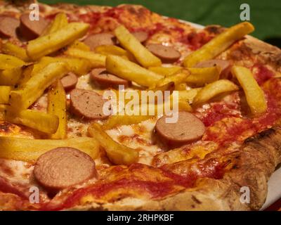 Une pizza garnie de frites et de tranches de hot-dog, surnommée humoristiquement « American Pizza », servie à Cuneo, Piémont, Italie Banque D'Images