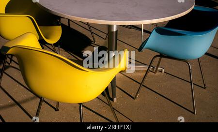 Chaises en plastique colorées modernes, vue abstraite, longues ombres dans l'après-midi Banque D'Images