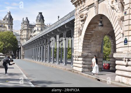 Jeune couple chinois et ami prenant des photos de mariage encadrés par l'arc de triomphe massif en pierre au centre du Pont de Bir Hakeim, à Paris Banque D'Images