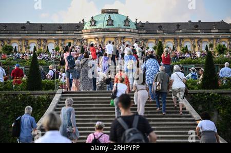 Potsdam, Allemagne. 18 août 2023. Visiteurs de la 25e nuit du palais de Potsdam dans le parc de Sanssouci, qui a lieu les 18 et 19 août. Avec le titre 'prachtig' une touche néerlandaise a été donnée au programme. Un monde de conte de fées de danse, théâtre, musique, acrobaties, lectures, des installations lumineuses et des délices culinaires seront proposés dans le parc du palais de Sanssouci. Crédit : Britta Pedersen/dpa/Alamy Live News Banque D'Images