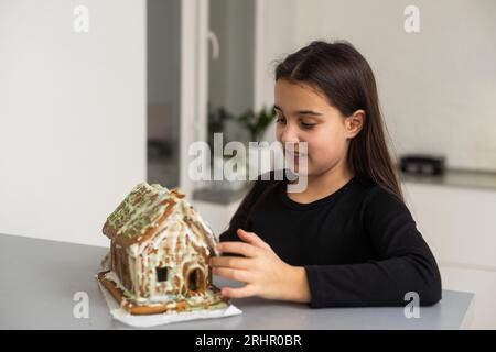 Une adolescente mange une maison de pain d'épice Banque D'Images