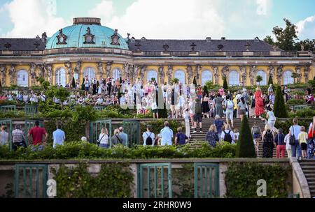 Potsdam, Allemagne. 18 août 2023. Visiteurs de la 25e nuit du palais de Potsdam dans le parc de Sanssouci, qui a lieu les 18 et 19 août. Avec le titre 'prachtig' une touche néerlandaise a été donnée au programme. Un monde de conte de fées de danse, théâtre, musique, acrobaties, lectures, des installations lumineuses et des délices culinaires seront proposés dans le parc du palais de Sanssouci. Crédit : Britta Pedersen/dpa/Alamy Live News Banque D'Images