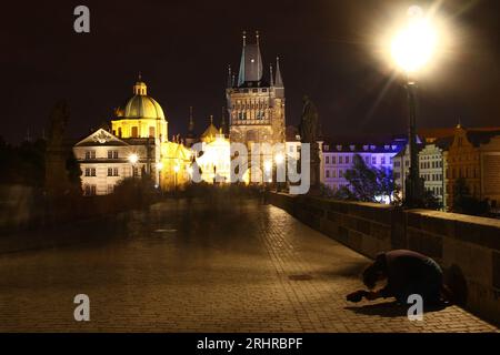 Pont Charles - Prague, République tchèque 2011 : prise de vue de nuit longue exposition avec des personnes floues et un mendiant en attente d'argent Banque D'Images