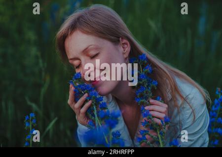 Portrait de jeune femme avec des fleurs bleues dans un champ Banque D'Images