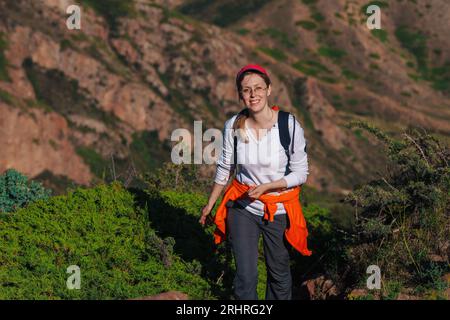 Jeune femme randonneur avec sac à dos marche le long d'un sentier de montagne Banque D'Images