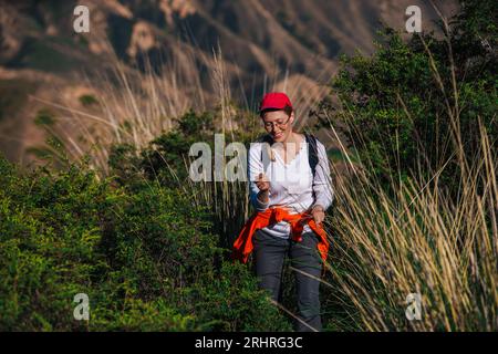 Jeune femme randonneur avec sac à dos marche le long d'un sentier de montagne Banque D'Images