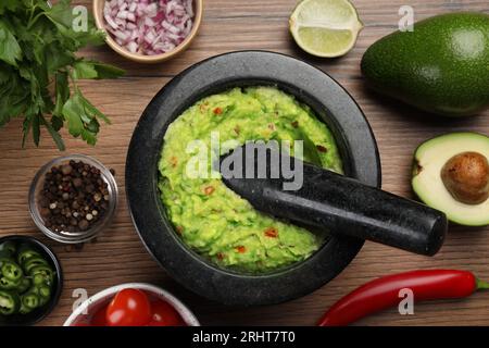 Délicieux guacamole dans le mortier et les ingrédients sur la table en bois, pose à plat Banque D'Images