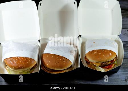 Pile de petits pains au sésame de patties de filet de poulet pané frit, laitue croustillante, fromage fondant, oignons et sauce, pâté de bœuf double épaisse juteuse avec chees Banque D'Images