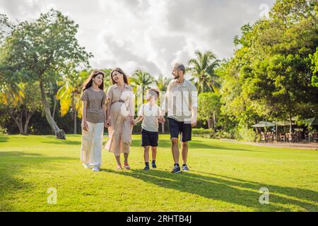 Une famille aimante profitant d'une promenade tranquille dans le parc - une femme enceinte radieuse après 40, embrassée par son mari, et accompagnée de leur adulte Banque D'Images