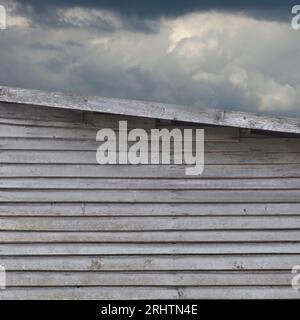 Vieux mur de cabane de ferme en bois abîmé gris naturel vieilli, grand fond vertical grungy rustique texturé, paysage nuageux de ciel moody, nuages sombres Banque D'Images