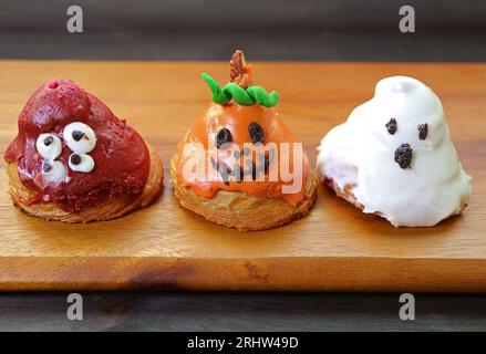 Rangée de croissants glacés au sucre en forme de Ghosts d'Halloween sur planche à pain en bois Banque D'Images