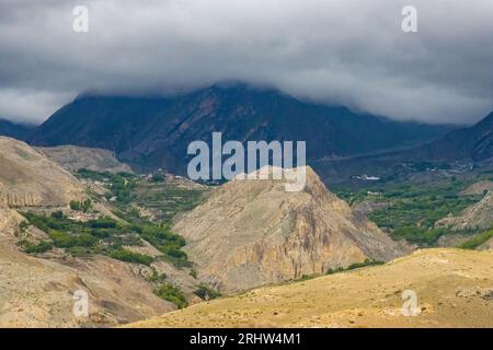 Paysage sombre et dramatique du désert avec montagnes Foggy et maisons lointaines à Muktinath, Mustang, Népal Banque D'Images