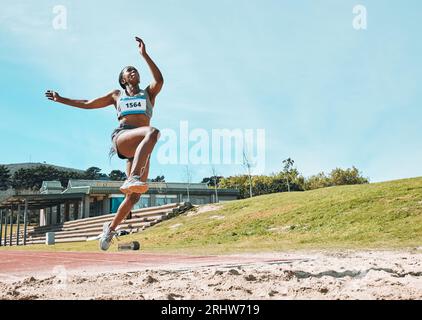 Athlétisme, condition physique et sport femme faisant du saut en longueur dans la compétition extérieure, le défi d'athlète ou l'entraînement. Agilité, bac à sable et entraînement de la personne féminine Banque D'Images