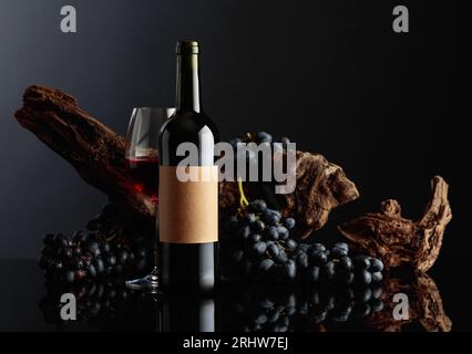 Bouteille de vin rouge avec vieille étiquette vide. En arrière-plan, de vieux accrochages altérés et des raisins bleus. Banque D'Images