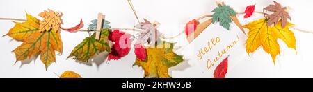 Composition créative de bordure de cadre d'automne avec feuilles d'automne. Les feuilles d'automne rouges et jaunes pendent sur corde à linge, sur fond blanc espace de copie pour t Banque D'Images