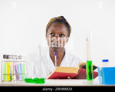 Jeune scientifique faisant ses recherches dans un laboratoire tout en consultant un manuel. Banque D'Images