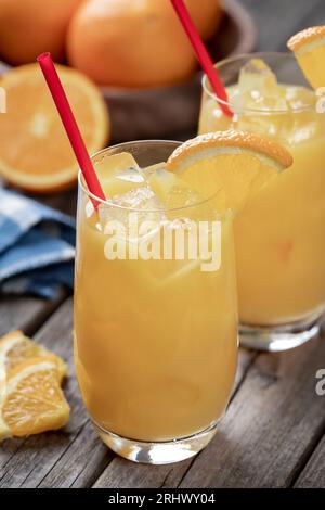 Cocktail de jus d'orange avec des tranches d'orange et des oranges fraîches sur une vieille table en bois Banque D'Images