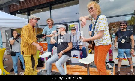 Hanovre, Allemagne. 19 août 2023. Gero Drnek (de gauche à droite), claviériste, Rainer Schumann, batteur, Kai Wingenfelder, chanteur, Thorsten Wingenfelder, guitariste, et Christof Stein-Schneider, guitariste, du groupe 'Fury in the Slaughterhouse' se produisent devant la branche d'une chaîne de pharmacies. Les six membres du groupe Fury in the Slaughterhouse sont assis à la caisse d'une pharmacie pendant une heure pour une bonne cause. La pharmacie fait don de tous les bénéfices à la fête annuelle de Noël pour les sans-abri et les nécessiteux à Hanovre. Crédit : Fernando Martinez/TNN/dpa/Alamy Live News Banque D'Images