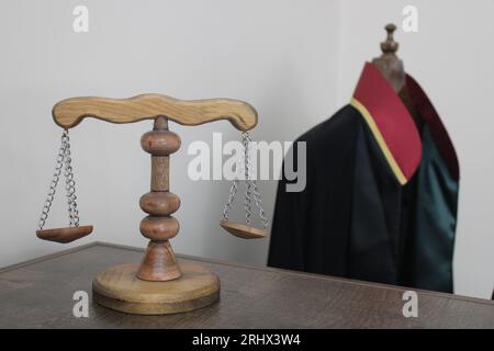 échelles de justice en bois, symbolisant la justice et le droit. robe d'avocat en arrière-plan. Banque D'Images