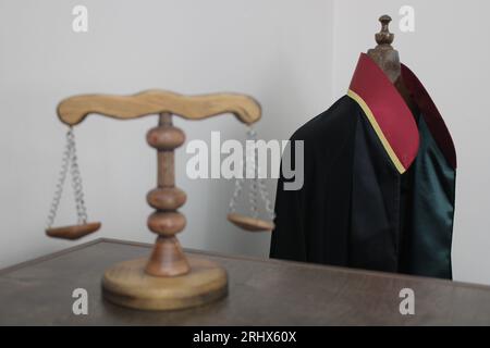 échelles de justice en bois, symbolisant la justice et le droit. robe d'avocat en arrière-plan. Banque D'Images