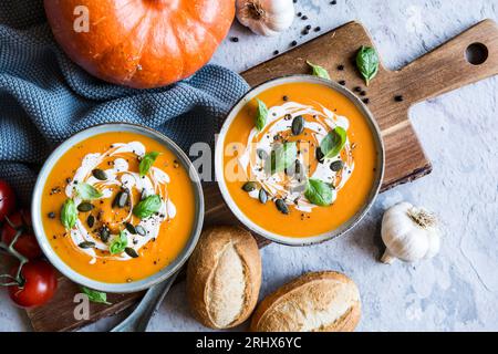 Soupe végétarienne à la citrouille et à la crème de tomates garnie de crème sure, de graines de citrouille et de basilic Banque D'Images