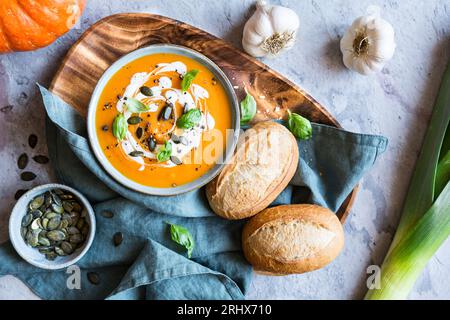 Soupe végétarienne à la citrouille et à la crème de tomates garnie de crème sure, de graines de citrouille et de basilic Banque D'Images