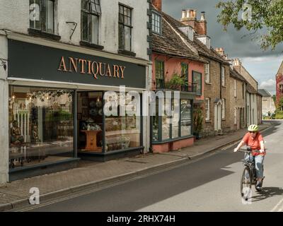 Un cycliste longe Abbey Row en face de l'abbaye historique dans la ville marchande de Malmesbury dans le Wiltshire. Banque D'Images