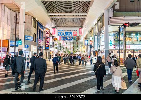 Vue nocturne le long de l'intérieur de la galerie marchande Shimotori occupé avec les gens faisant du shopping et utilisant les nombreux restaurants. Kumamoto, Japon. Banque D'Images