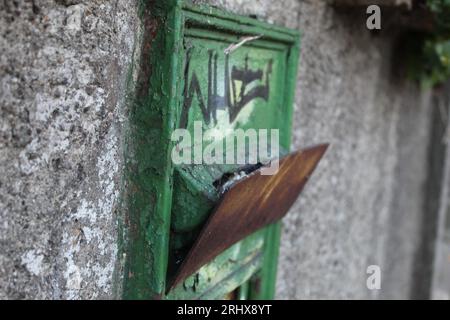 Une photo d'une vieille boîte aux lettres verte dans un mur de pierre. Banque D'Images