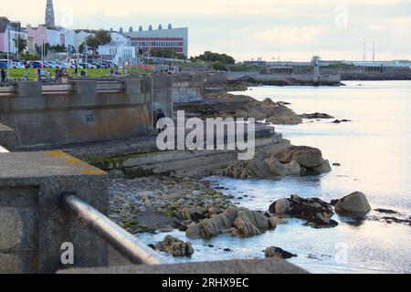 Une photo d'une promenade le long du bord d'une côte et le paysage des bâtiments derrière elle. Banque D'Images