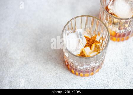Angle élevé de verres de whisky avec de la glace et de la peau d'orange placé sur fond gris Banque D'Images