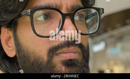 Gros plan pensif sérieux visage masculin yeux dans des lunettes regardant la distance. Homme d'affaires barbu indien arabe pense regarder de côté dans les lunettes. Man In Banque D'Images