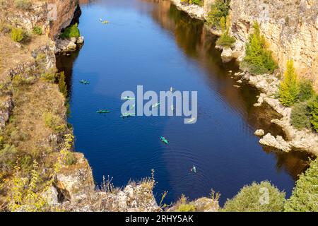 Réserve naturelle de Hoces del Rio Duraton (Parque Natural de las Hoces del Río Duratón) avec falaises verticales calcaires, eau bleue et kayaks colorés. Banque D'Images