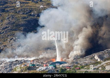 Hélicoptère larguant de l'eau sur un incendie à Qaqortoq, Groenland Banque D'Images